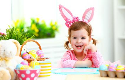 Easter. happy child girl with bunny ears decorates the home for Easter colored eggs and flowers