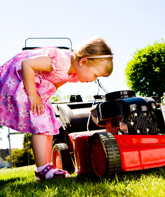 a 3,5 years old girl with lawnmower in the garden